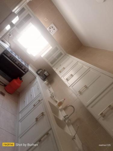 a small kitchen with white cabinets and a window at فيلا سعد in Riyadh