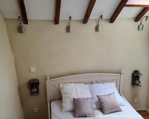 une chambre avec un lit avec des draps blancs et des oreillers dans l'établissement Le Gatu by Les Gîtes de la Jonte, à Gatuzières