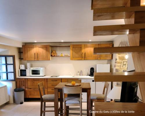 une cuisine avec des armoires en bois et une table et des chaises dans l'établissement Le Gatu by Les Gîtes de la Jonte, à Gatuzières