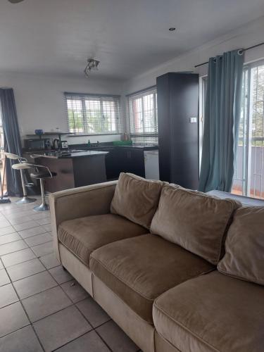 een woonkamer met een bruine bank en een keuken bij Morningview Cottage - Self Catering Private Owned Rental in Durban