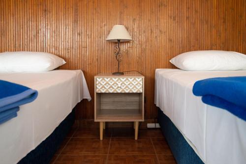 two beds in a room with a table with a lamp at Hôtel Argo in Volos