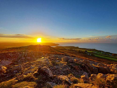 a sunset on top of a mountain with the ocean at Clyne Farm Centre in The Mumbles
