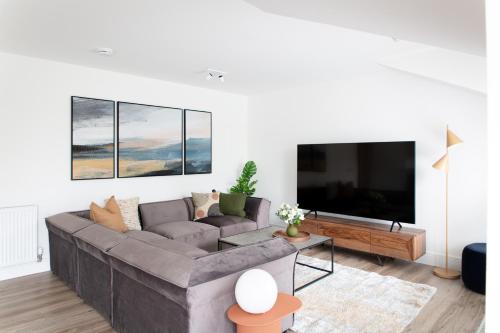 a living room with a gray couch and a flat screen tv at Penthouse Apartment at Loch Lomond with 2 bedrooms in Balloch