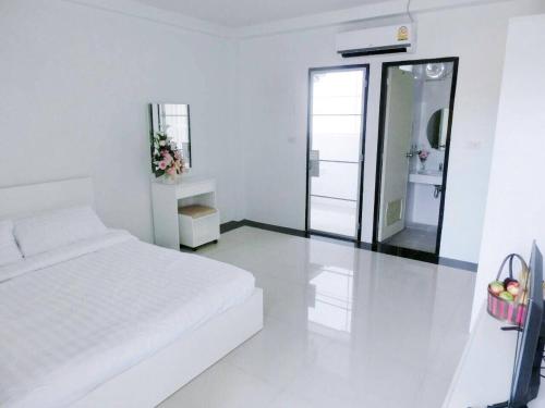 a white bedroom with a bed and a mirror at Pichayapa Place in Ban Pa Sang (1)