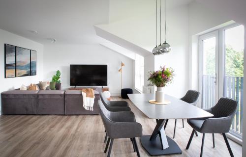 a living room with a table and chairs and a couch at Penthouse Apartment at Loch Lomond with 2 bedrooms in Balloch