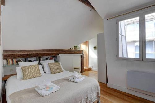 une chambre avec un grand lit blanc et une fenêtre dans l'établissement Loft place des Vosges, à Paris