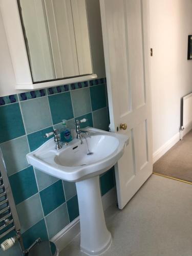 baño con lavabo blanco y azulejos azules en Ramblers, Burley, New Forest, en Burley