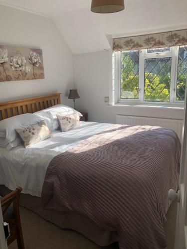 Un dormitorio con una cama y dos ventanas. en Ramblers, Burley, New Forest, en Burley