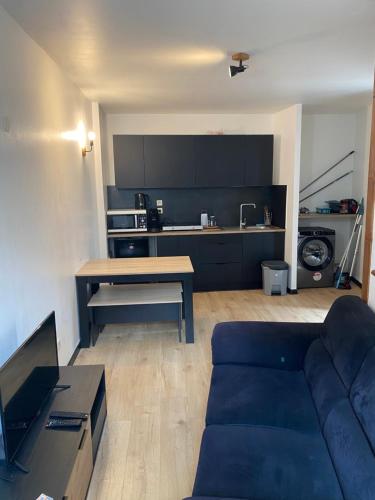 un salon avec un canapé bleu et une cuisine dans l'établissement Petite maison de charme, à Saint-Rambert-en-Bugey