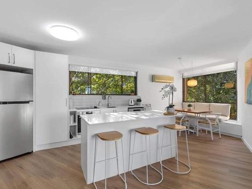 a white kitchen with a large white island with stools at Young unit3 Lake Access in Nagambie