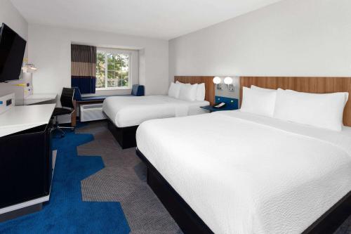 a hotel room with two beds and a desk at Microtel Inn by Wyndham Janesville in Janesville