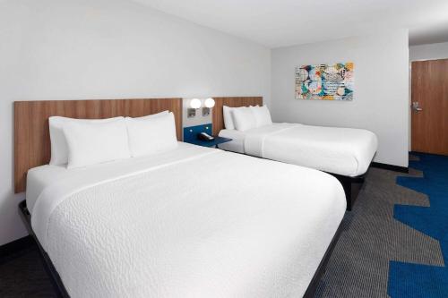 two beds in a hotel room with white sheets at Microtel Inn by Wyndham Janesville in Janesville