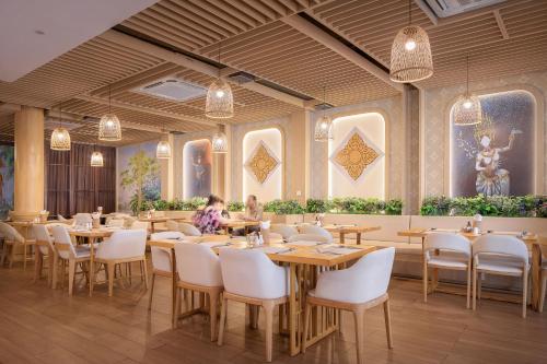 a restaurant with tables and chairs and paintings on the walls at G Mekong Hotel Phom Penh in Phnom Penh