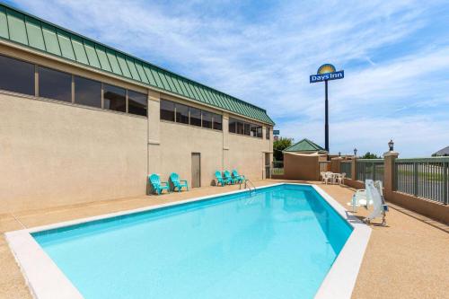 a swimming pool with chairs and a building at Days Inn by Wyndham Clarksville North EXIT 4 in Clarksville