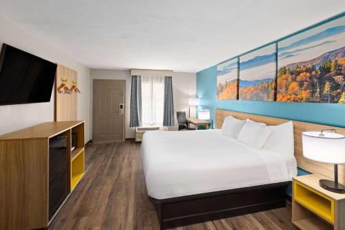 a hotel room with a bed and a flat screen tv at Days Inn by Wyndham Clarksville North EXIT 4 in Clarksville