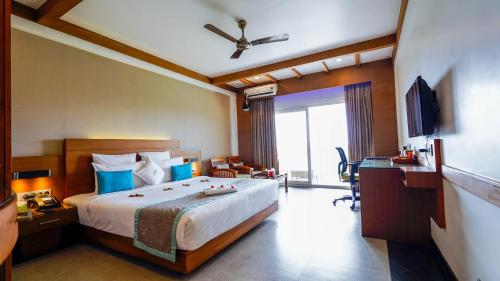 a bedroom with a bed and a desk and a television at Chandys Windy Woods Munnar in Munnar