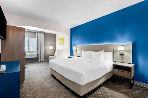a large white bed in a room with a blue wall at Comfort Suites Denver North - Westminster in Westminster