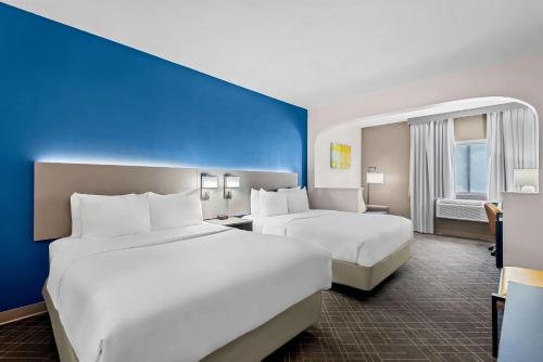 two beds in a hotel room with blue walls at Comfort Suites Denver North - Westminster in Westminster