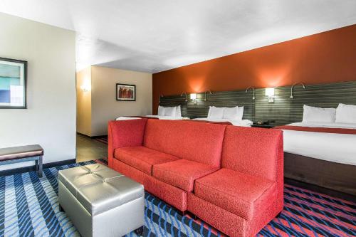 a hotel room with a bed and a red couch at Comfort Suites Fairgrounds West in Oklahoma City