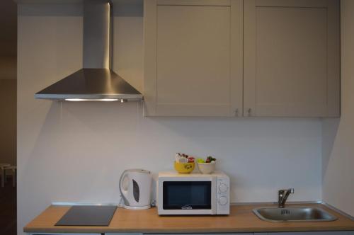 a kitchen counter with a microwave and a sink at CBA Suites Madeira in Funchal