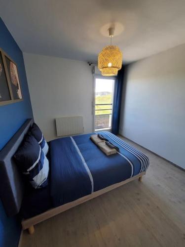 une chambre avec un lit bleu dans une pièce avec une fenêtre dans l'établissement T4 terrasse et box - Groupama Stadium-Eurexpo-Lyon, à Meyzieu