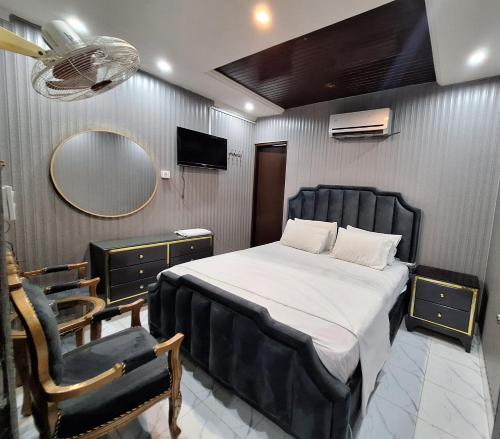Un dormitorio con una cama, una silla y un espejo. en Divine Hotel Lahore, en Lahore