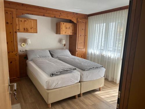 a bedroom with a large bed with a wooden headboard at Hotel Adonis in Zermatt