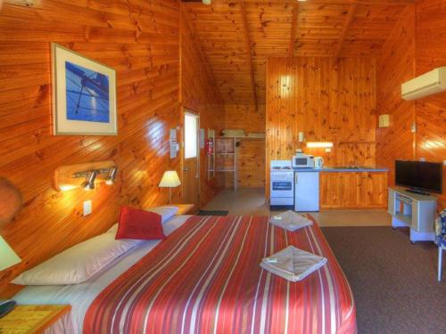 a bedroom with a large bed in a wooden cabin at BIG4 Low Head Tourist Park in Low Head