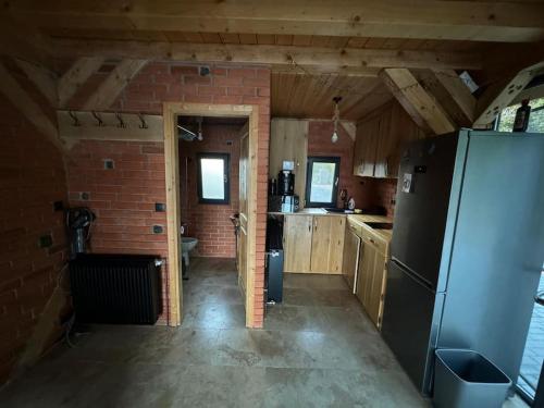 a kitchen with a refrigerator and a brick wall at Cabana lac Apa Stefania in Medieşu Aurit