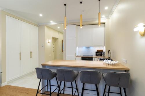 a kitchen with a island with four bar stools at Luxury Central Apartment in Putvinskio street in Kaunas