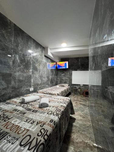 a room with two beds and a tv on the wall at Berić Rooms in Šabac