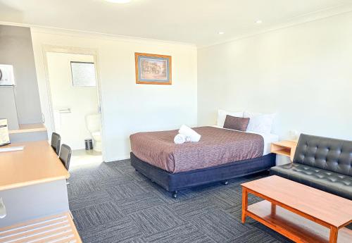 a hotel room with a bed and a couch at Ascot Lodge Motor Inn in Kingaroy