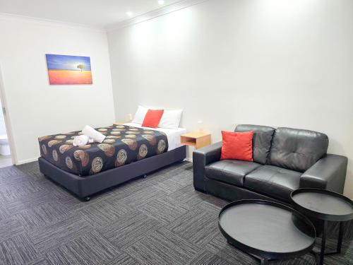 a living room with a couch and a bed at Ascot Lodge Motor Inn in Kingaroy