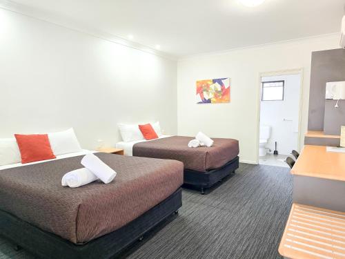 a hotel room with two beds and a desk at Ascot Lodge Motor Inn in Kingaroy