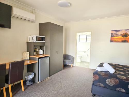 a room with a bed and a desk and a kitchen at Ascot Lodge Motor Inn in Kingaroy