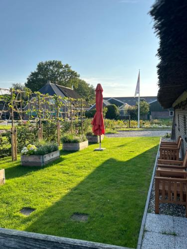a garden with a red umbrella in the grass at Hof van Balloo in Balloo