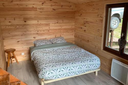 une chambre avec un lit dans une cabane en rondins dans l'établissement Gîte du Lilas, à Mortagne