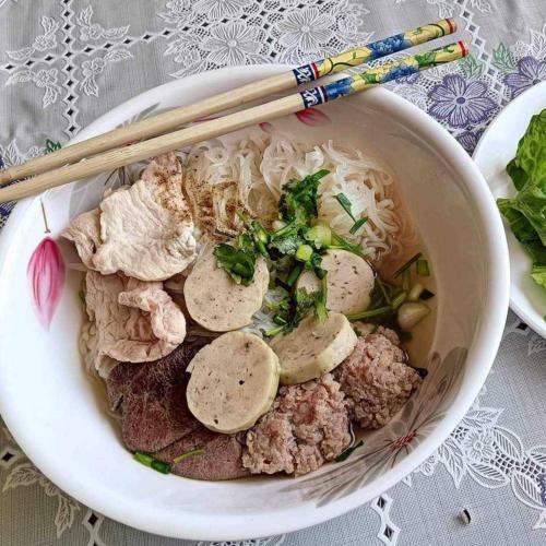 a bowl of soup with meat and vegetables and chopsticks at PS Hotel Saraburi in Sara Buri