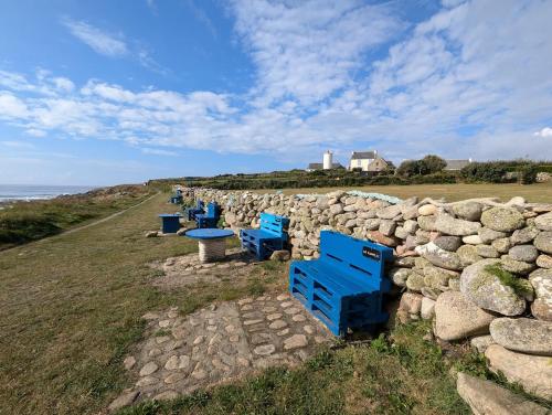 a row of blue benches next to a stone wall at La Tour du Bois Dormant in Plozévet