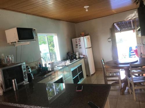 una cucina con bancone, tavolo e frigorifero di Sítio Recanto do Pardal a Santa Rita de Caldas