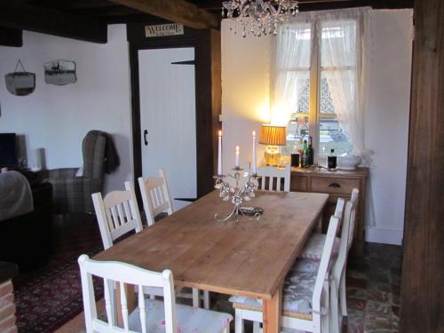 une salle à manger avec une table en bois et des chaises blanches dans l'établissement Maison de tante Alice, à Haravesnes