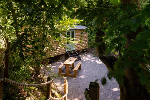 a picnic table and a bench in front of a cabin at Bijoux Shepherds Hut Lyme Regis in Lyme Regis