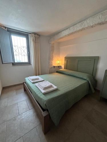 a bedroom with a large green bed with a window at iCONICO - Authentic Trulli Experience in Cisternino