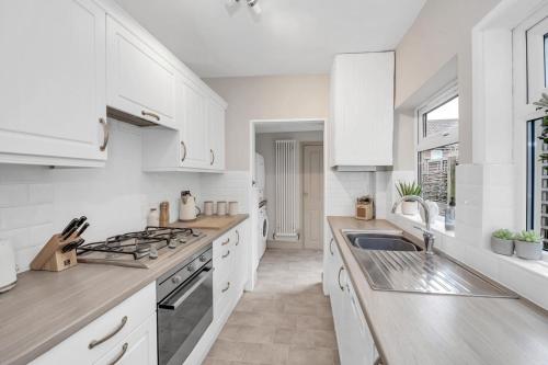 a white kitchen with white cabinets and a sink at Delightful 10 St Martins - 2 bed, 2 bathroom with parking available in Bury Saint Edmunds