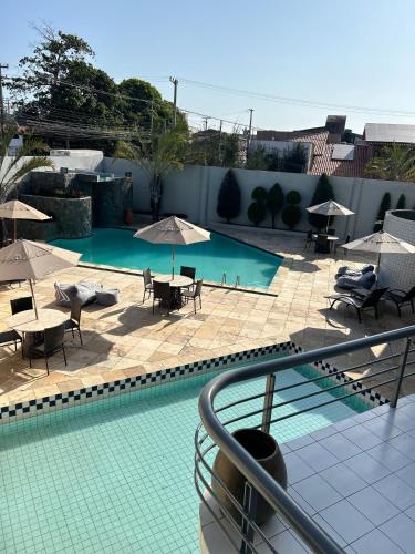 a swimming pool with tables and chairs and umbrellas at Nautillus Hotel in Parnaíba