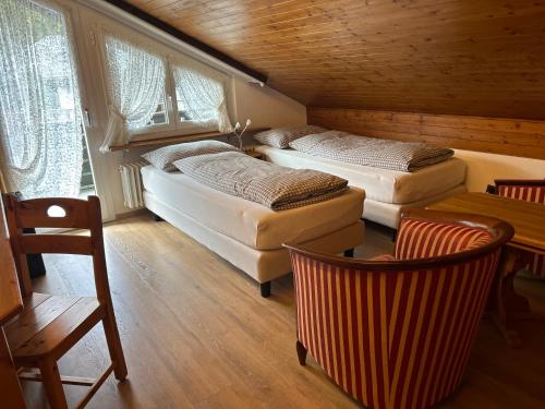 a bedroom with two beds and a table and chairs at Hotel Adonis in Zermatt