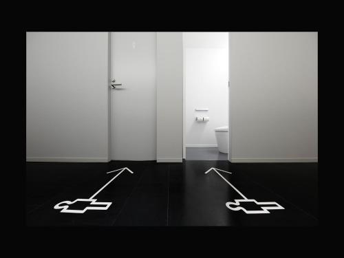 a bathroom with two white doors with arrows on the floor at nine hours Sendai in Sendai