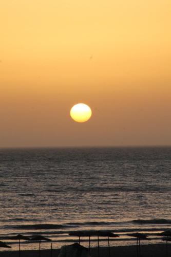 a sunset over the ocean with the sun in the sky at aziz house of surfing in Tagant