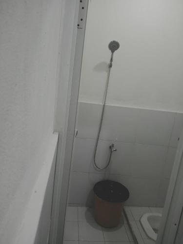 a bathroom with a shower with a toilet and a bucket at Rumah Putih Edi in Sengkol