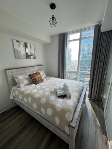 a bedroom with a large bed with a large window at Prestigious 2-Bdrm Condo - across from Scotiabank Arena in Toronto